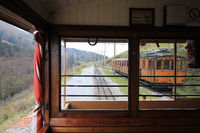 Croisement d’un train de la Rhune vu depuis un wagon d’un autre train ; à l’arrière-plan, le machiniste vient de changer manuellement l’aiguillage